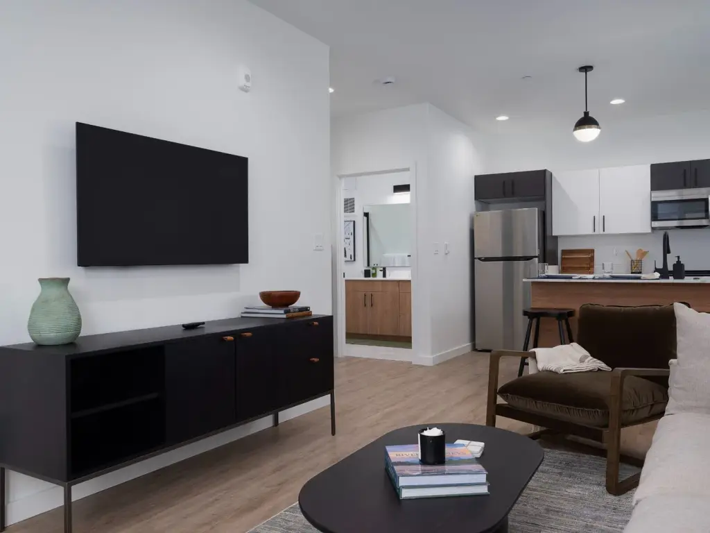 A furnished Teton Flats model living room with an open kitchen, wood flooring, and stainless appliances