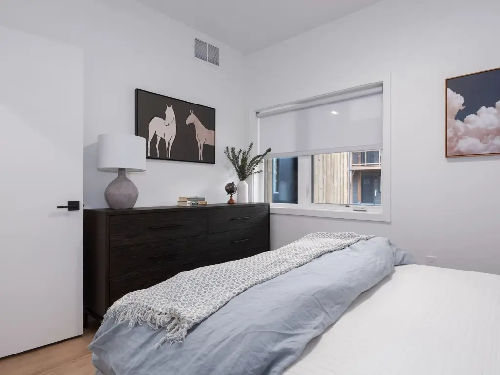 Staged one-bedroom model bedroom with a dresser and window