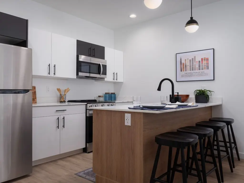 Staged one-bedroom model kitchen with stainless appliances and a breakfast bar